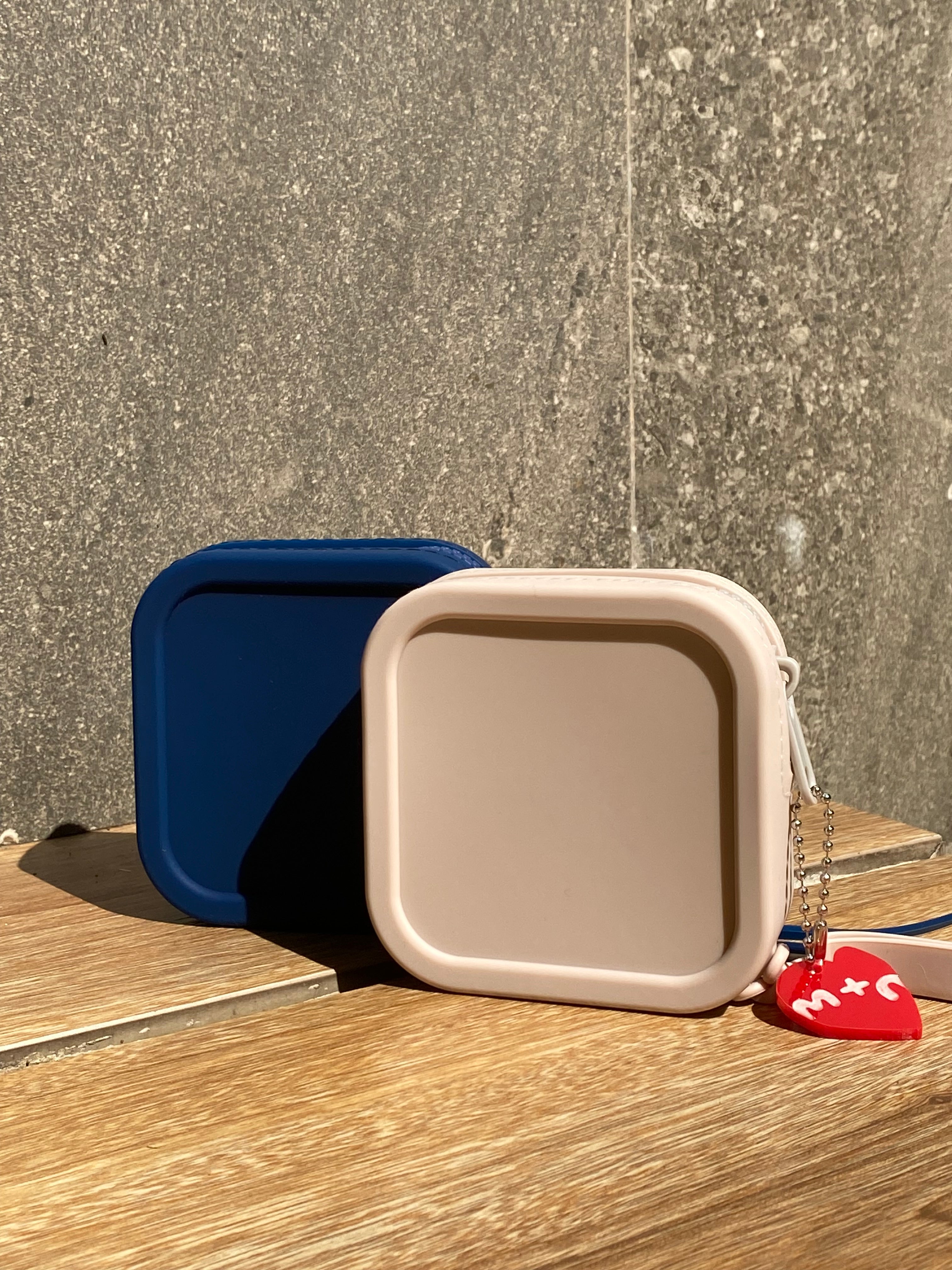 Beige and blue pet carrier on a wooden floor with a textured gray floor in the background