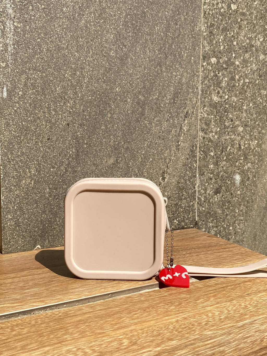 Beige square container with a red tag attached to a wooden surface on a concrete floor.