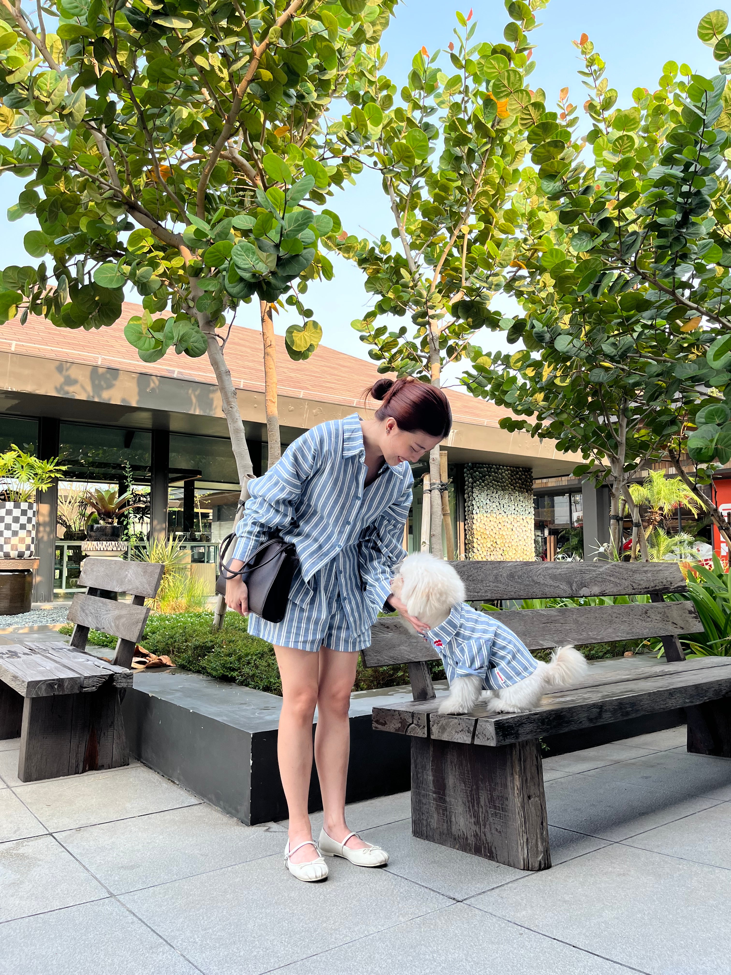 Two people sitting on a bench under a tree with a building in the background