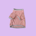 Pink dog sweater with gray trim on a light purple background