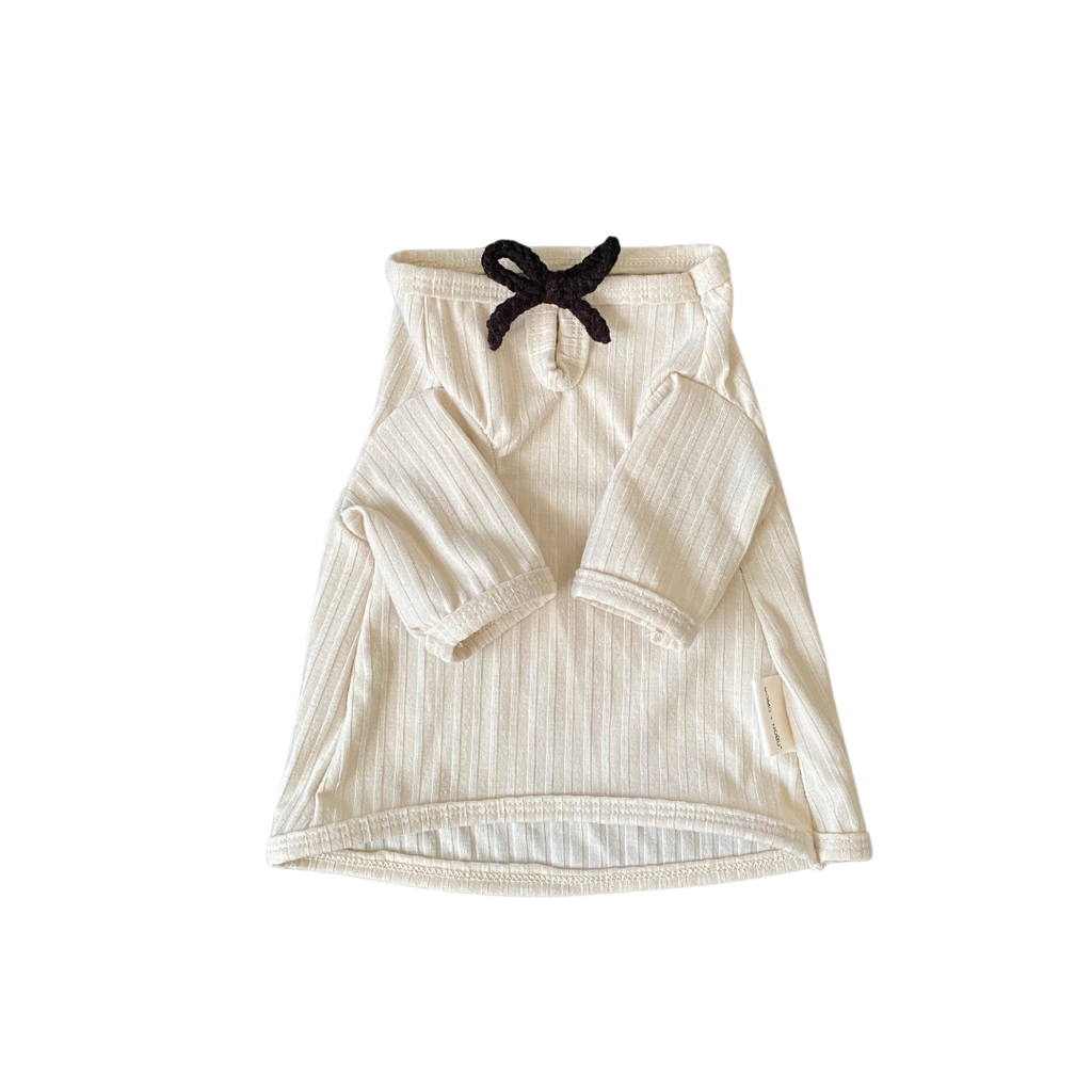 Beige baby outfit with black bow on a white background