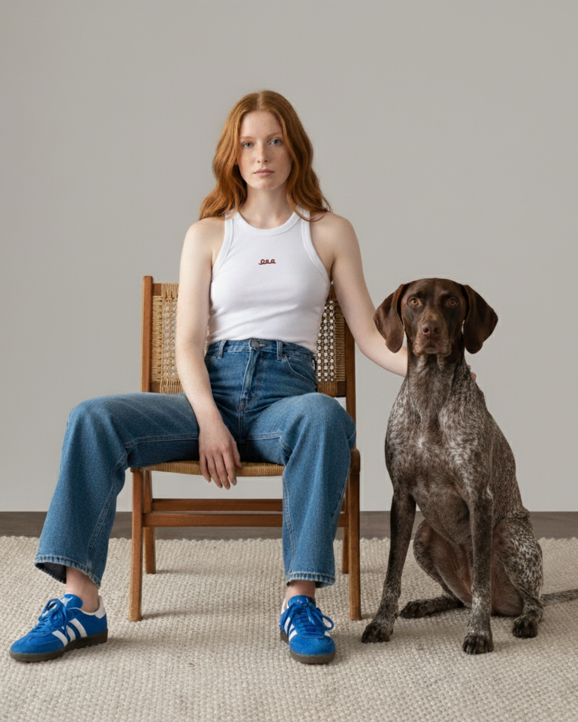 Woman sitting on a chair with a dog on a carpeted floor.