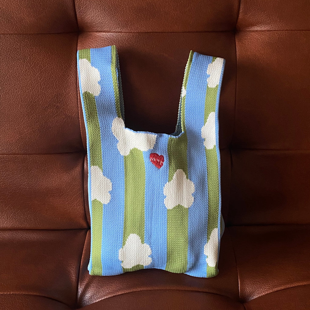 Knitted bag with cloud pattern on a brown leather couch