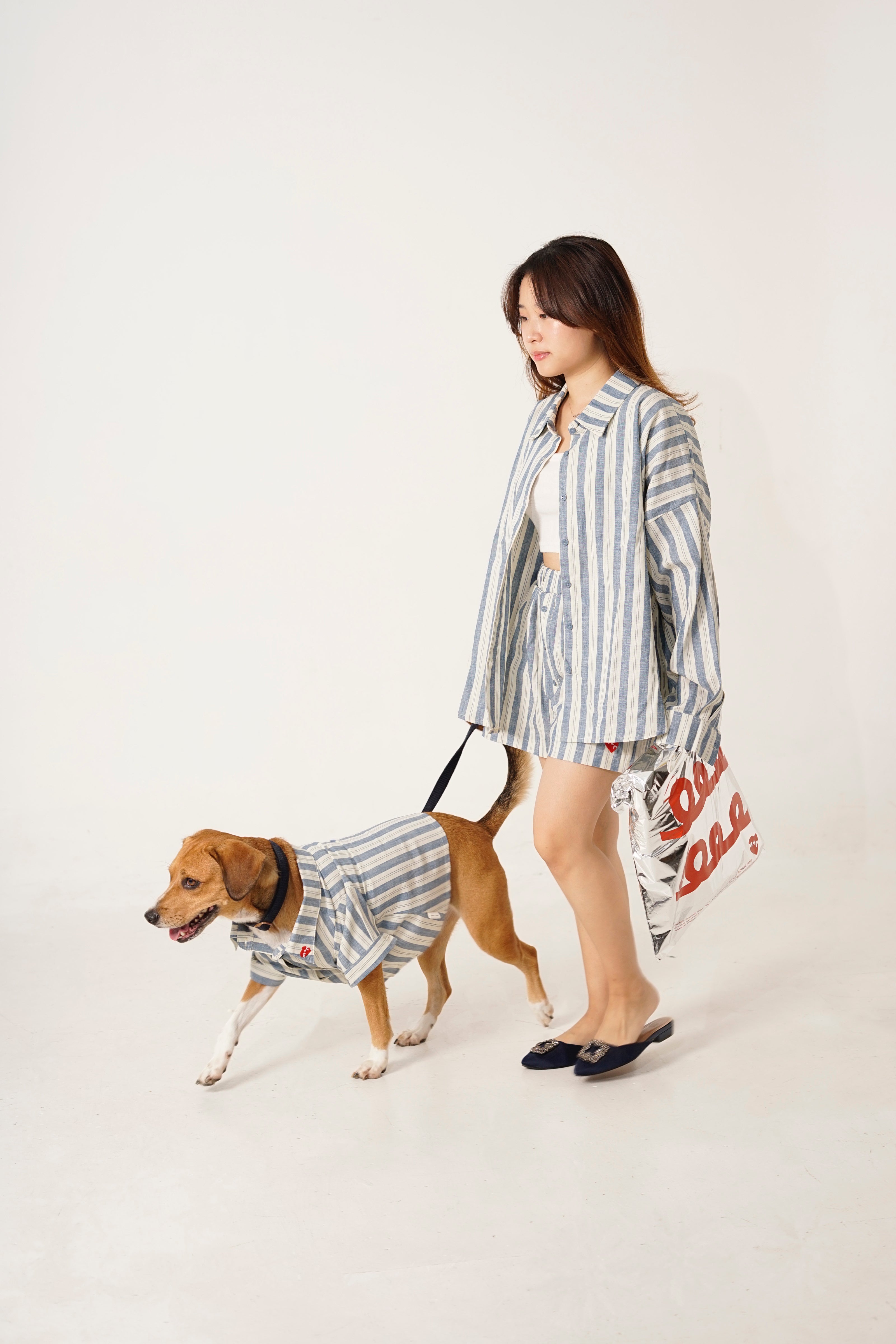 Woman and dog wearing matching striped outfits on a white background