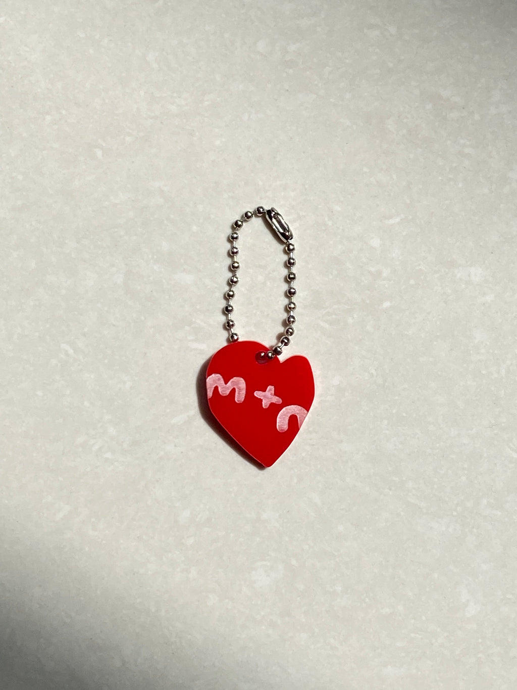 Red heart-shaped keychain with white text on a light gray background