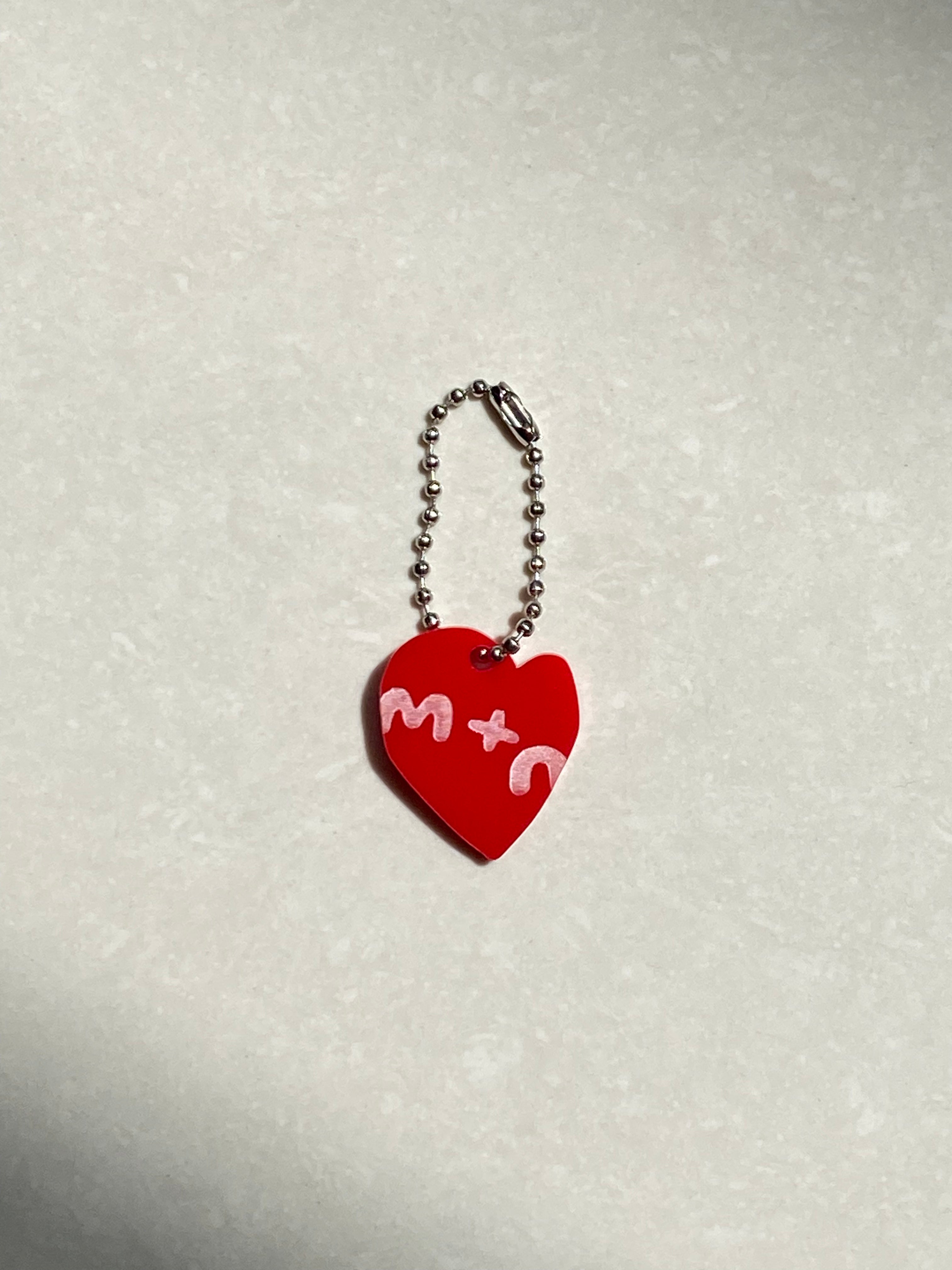 Red heart-shaped keychain with white text on a light gray background