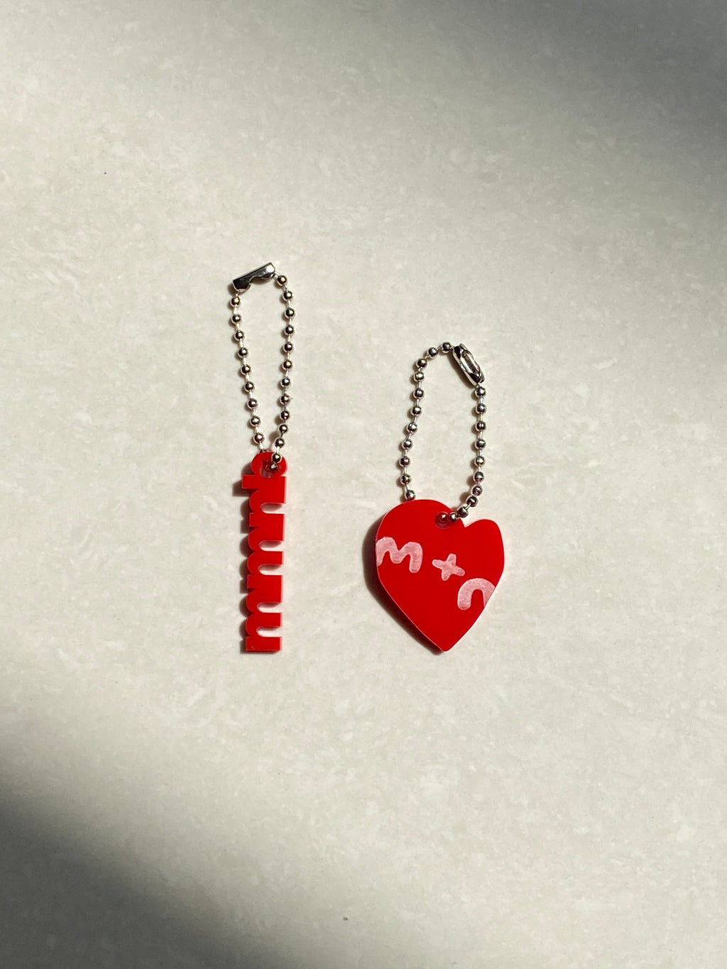 Two red keychains with metal chains on a light gray background