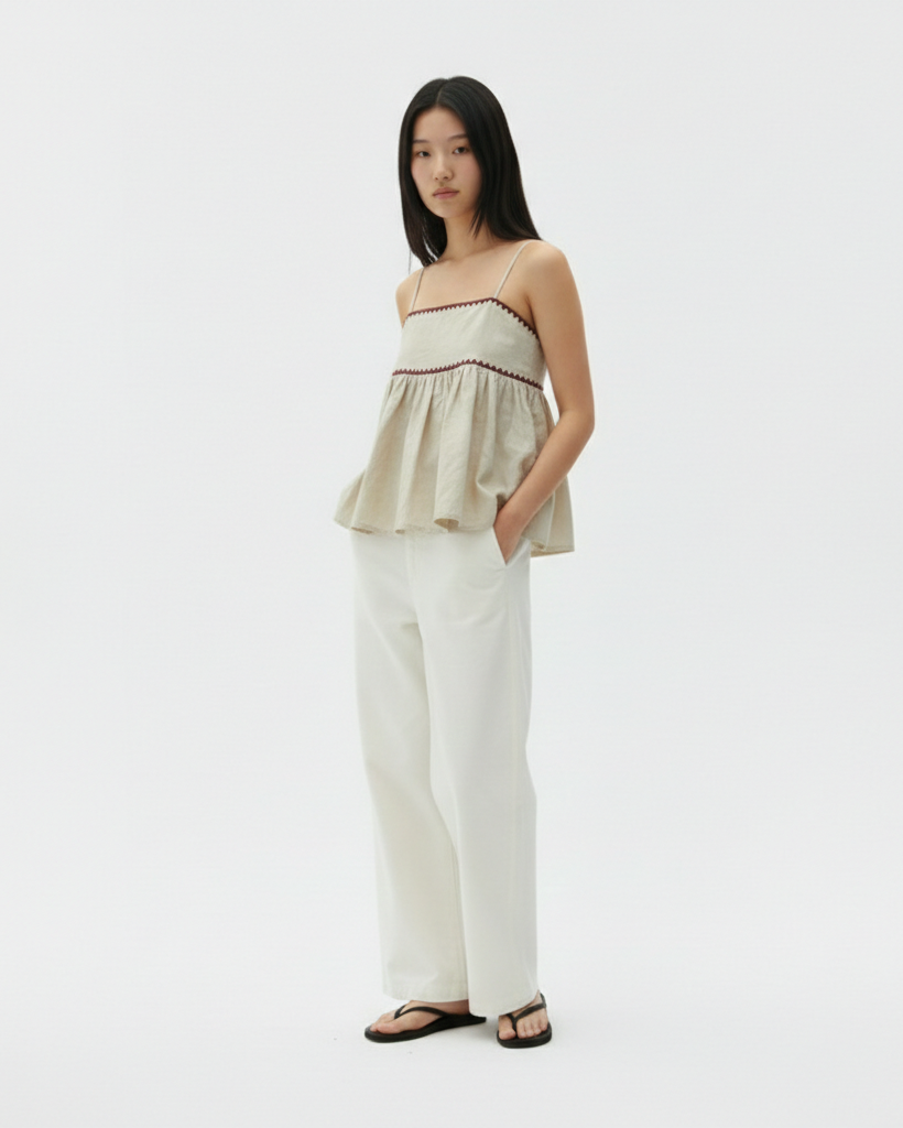 Woman wearing a strapless top and white pants on a light gray background