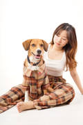 Woman and dog wearing matching plaid outfits on a white background